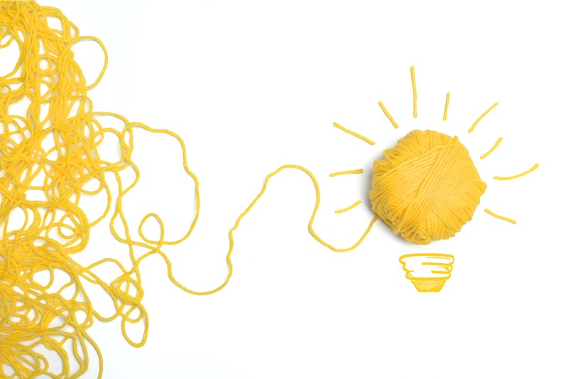 Un ovillo de lana amarilla formando una bombilla, representando una idea creativa